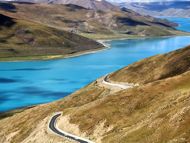 Yamdrok Tso lake on sunny day in Tibet with Friendship Highway