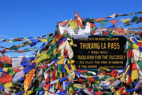Prayer flags and signboard on the Thorang La mountain pass, Annapurna Circuit & Tilicho Lake Trek 16 Days