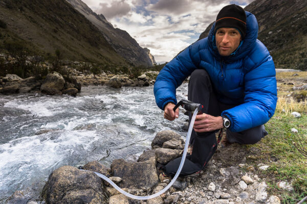 A Man Using Filtration System In Fast Running Stream