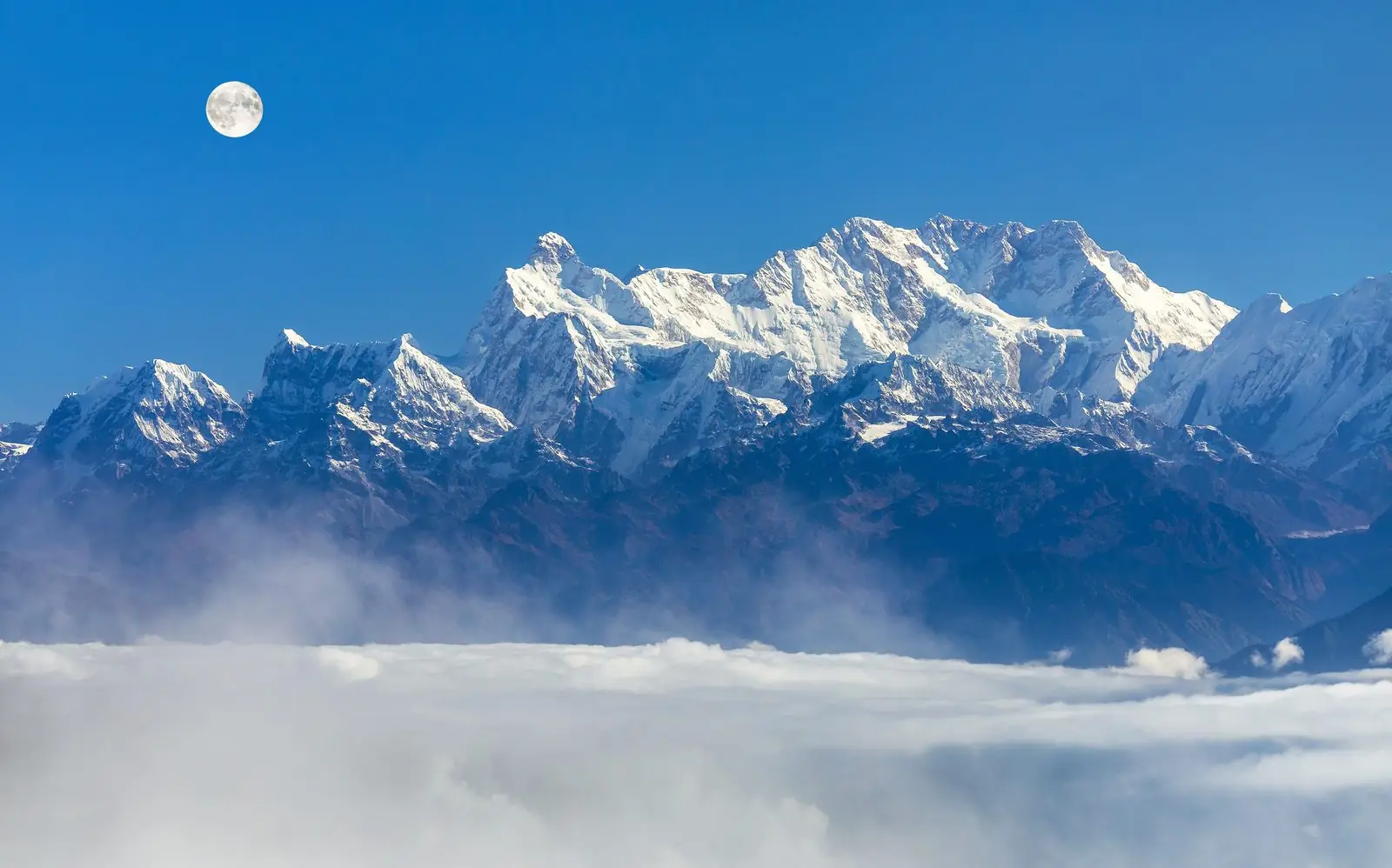 Kanchenjunga, 8,586 m, the second highest mountain in Nepal, with a full moon above the clouds